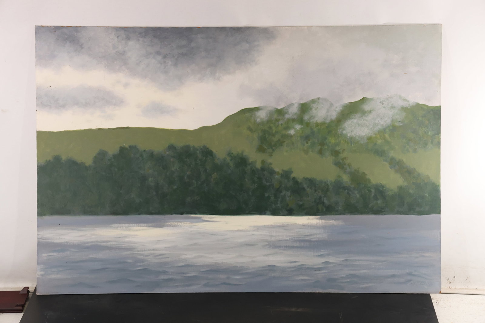R. Angeloch Loch Ness Landscape Painting on Board: A painting on board by R. Angeloch depicting Loch Ness beneath a clouded sky. Green wooded hills rise behind a broad stretch of water. The reverse bears a handwritten Loch Ness identification. Size: 3