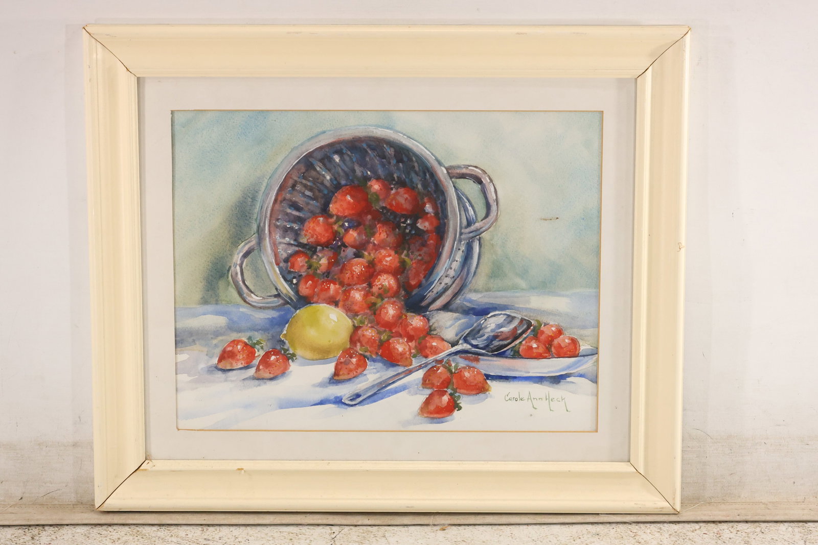 Carole Ann Heck Strawberries Still-Life Watercolor: A watercolor on paper signed "Carole Ann Heck" at lower right. Red strawberries spill from a tipped metal colander onto a pale cloth, with a yellow lemon and silver-toned tableware nearby. Cool blue s