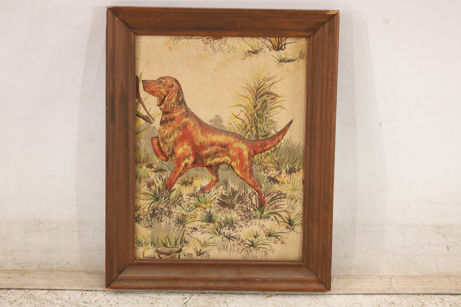 Framed Sporting Dog Textile Picture: A decorative textile picture depicting a red-brown setter standing alert among grasses and reeds. The fabric has a softly raised, padded appearance within a deep wood frame. A Bob Van Huizen