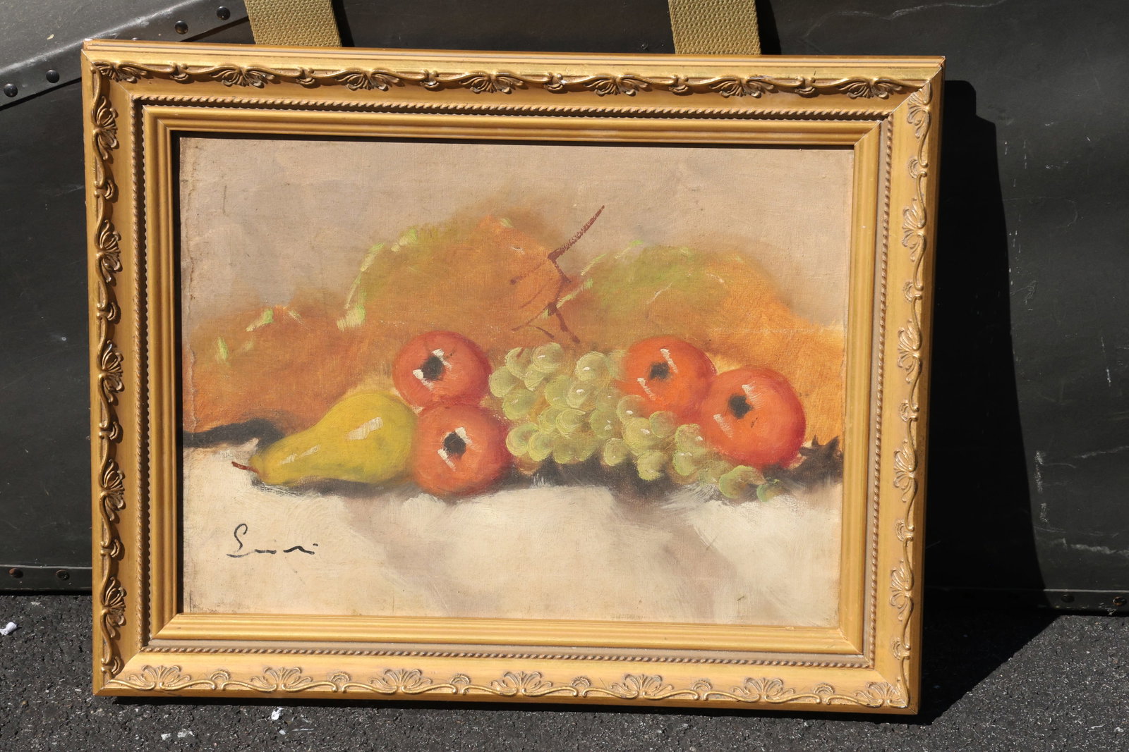 Signed Pear Apples and Grapes Still Life Painting: A small still-life painting depicting a yellow pear, red apples, and pale grapes arranged on a light cloth. Warm brown and orange background tones complement the fruit. Bears an indistinct signature a