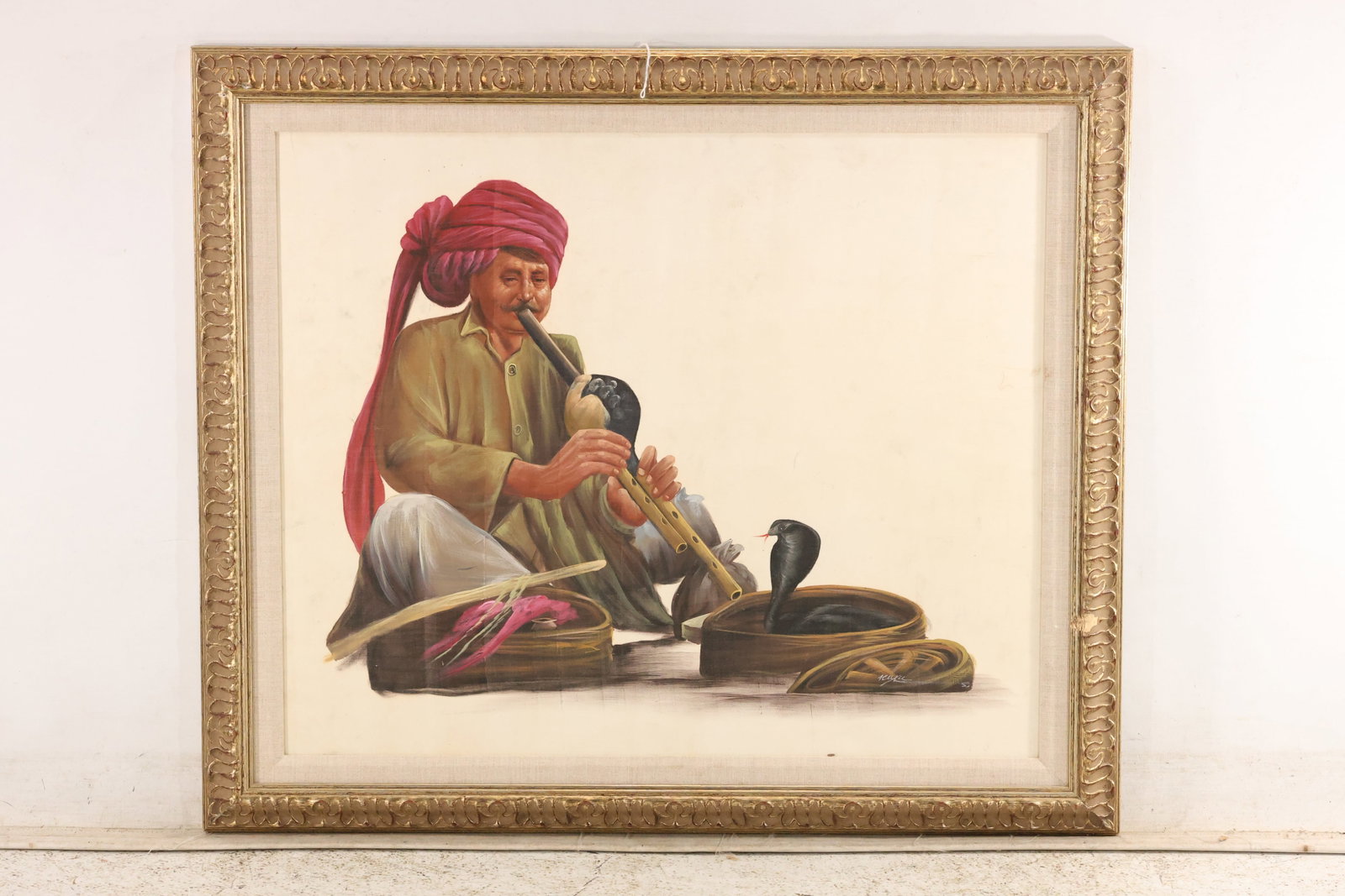 Signed Snake Charmer Painting on Canvas: Painting on canvas depicting a seated snake charmer in a red turban playing a wind instrument beside woven baskets and an upright cobra. Earth tones and detailed modeling contrast with the plain cream