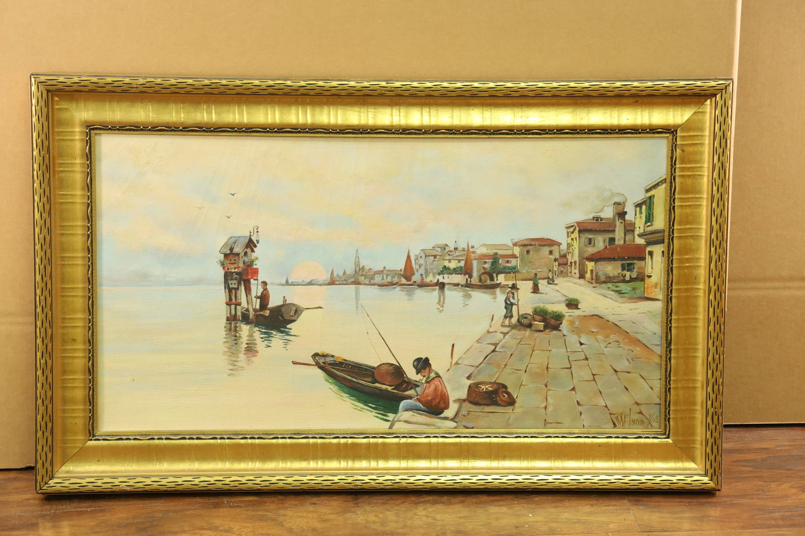 Venetian Waterfront Painting Signed W Flynn 9/28: Horizontal waterfront painting with small boats, figures on a paved quay, waterfront buildings and distant towers beneath a pale sky. Warm cream and ochre architecture contrasts with blue green water.