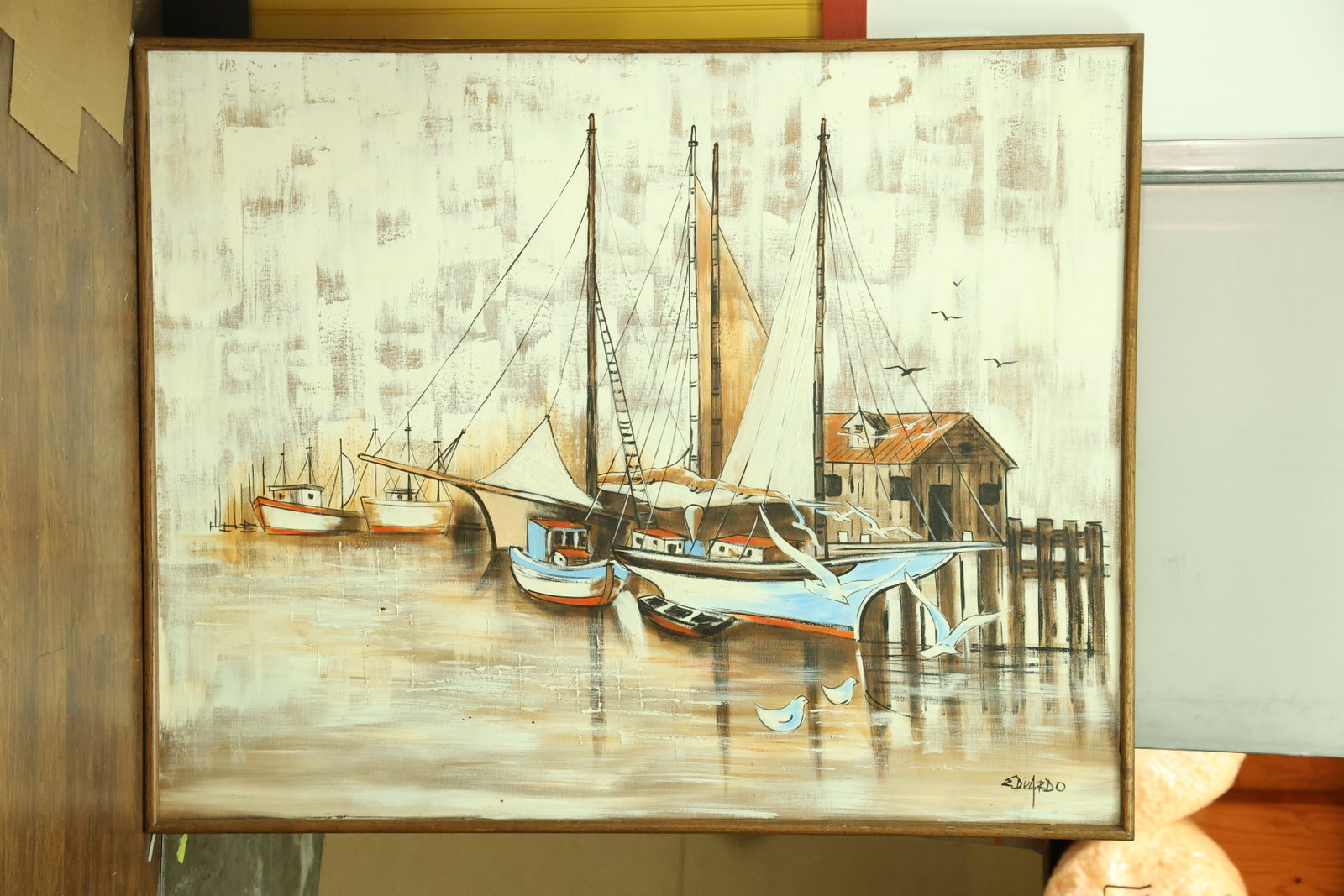 Harbor Boats and Seabirds Painting Signed Eduardo: Horizontal painting on canvas depicting docked boats with tall masts and dark rigging. White seabirds cross a textured gray cream and brown harbor scene. Black outlines define hulls and waterfront str