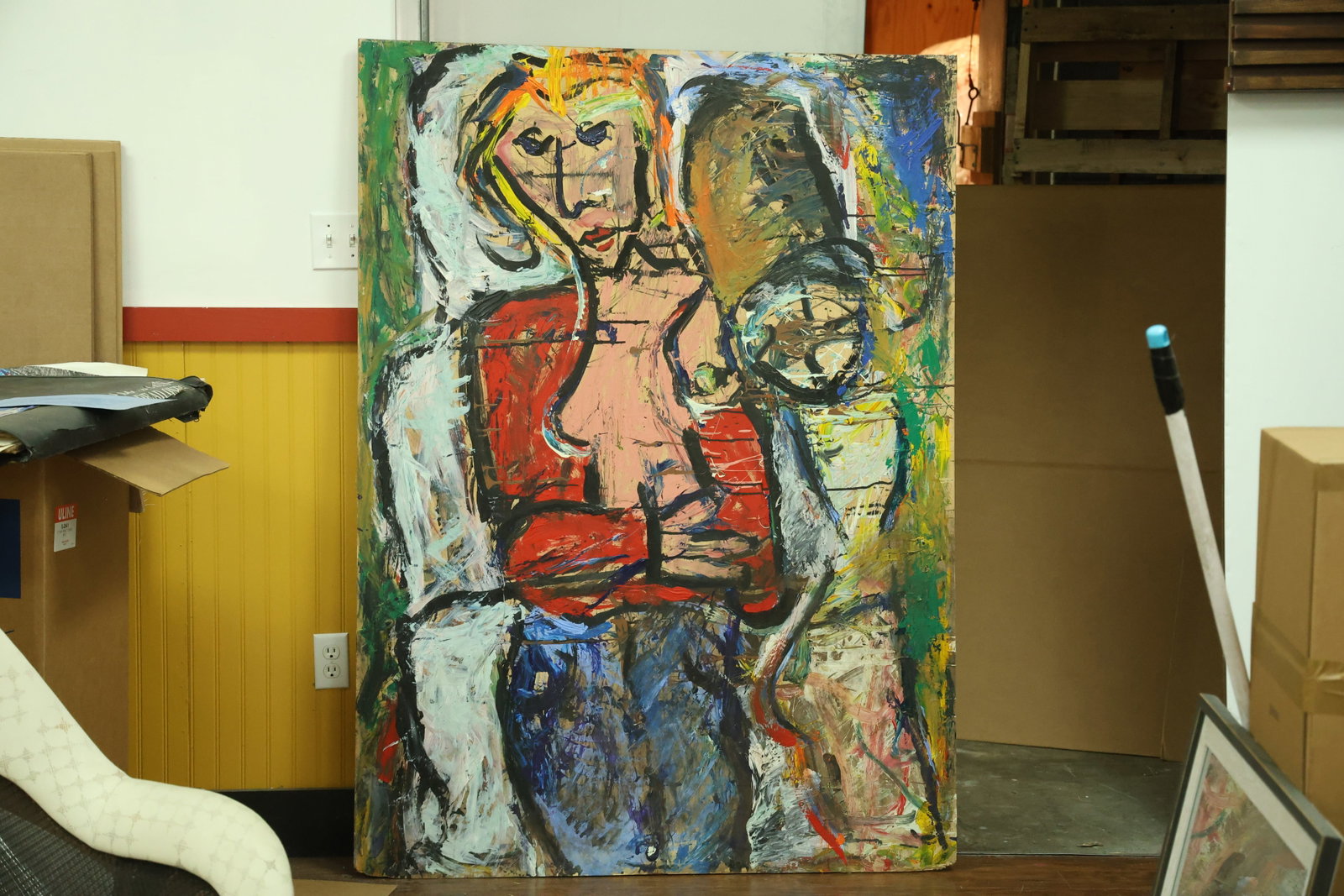 Large Expressionist Figure Painting on Plywood: Vertical painting on plywood depicting a stylized figure with red sleeves, blue trousers and a pink torso outlined in black. Yellow marks surround the head, with broad white green brown and blue strok