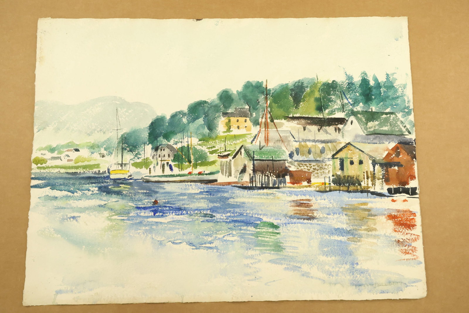 Waterfront Village and Boats Watercolor Attributed to Franklin Shores: Watercolor on paper with pale yellow and gray waterfront buildings, boat masts and dark green trees on a hillside. Loose blue, green and orange marks describe reflections across the foreground water. 