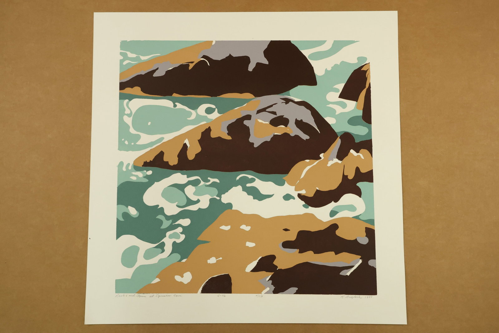 Rocks and Foam at Squeaker Cove Print Signed R Angeloch 1988 Marked A/P/III: Color print on paper with dark brown rocks, ochre highlights and curling cream foam against green blue water. The lower margin is titled Rocks and Foam at Squeaker Cove, signed R Angeloch, dated 1988 