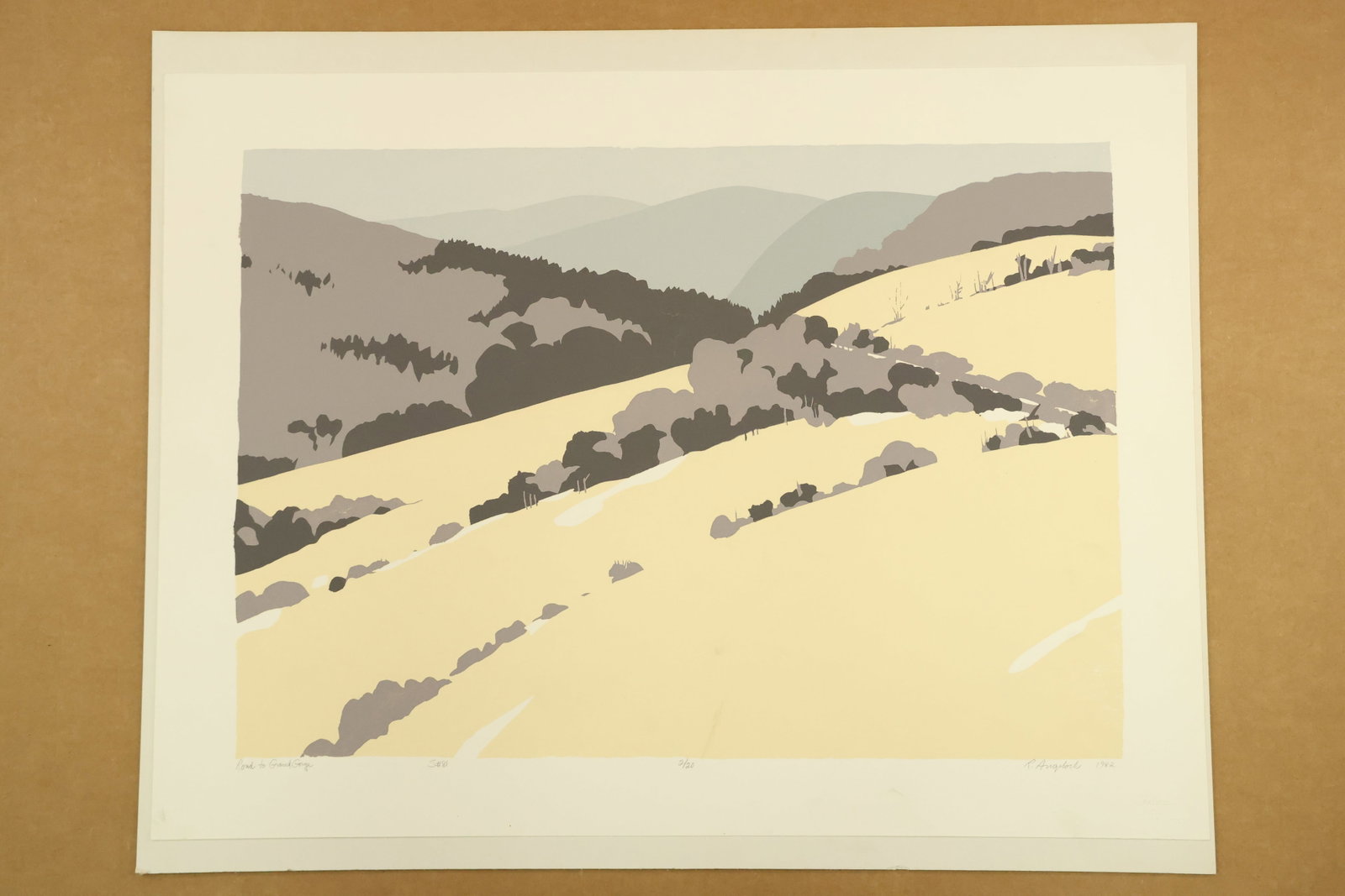 Road to Grand Gorge Color Print Signed R Angeloch 1982 Numbered 2/20: Color landscape print mounted on board, with pale yellow slopes and layered gray hills divided by dark trees and a narrow light road. Titled Road to Grand Gorge, signed R Angeloch, dated 1982 and numb