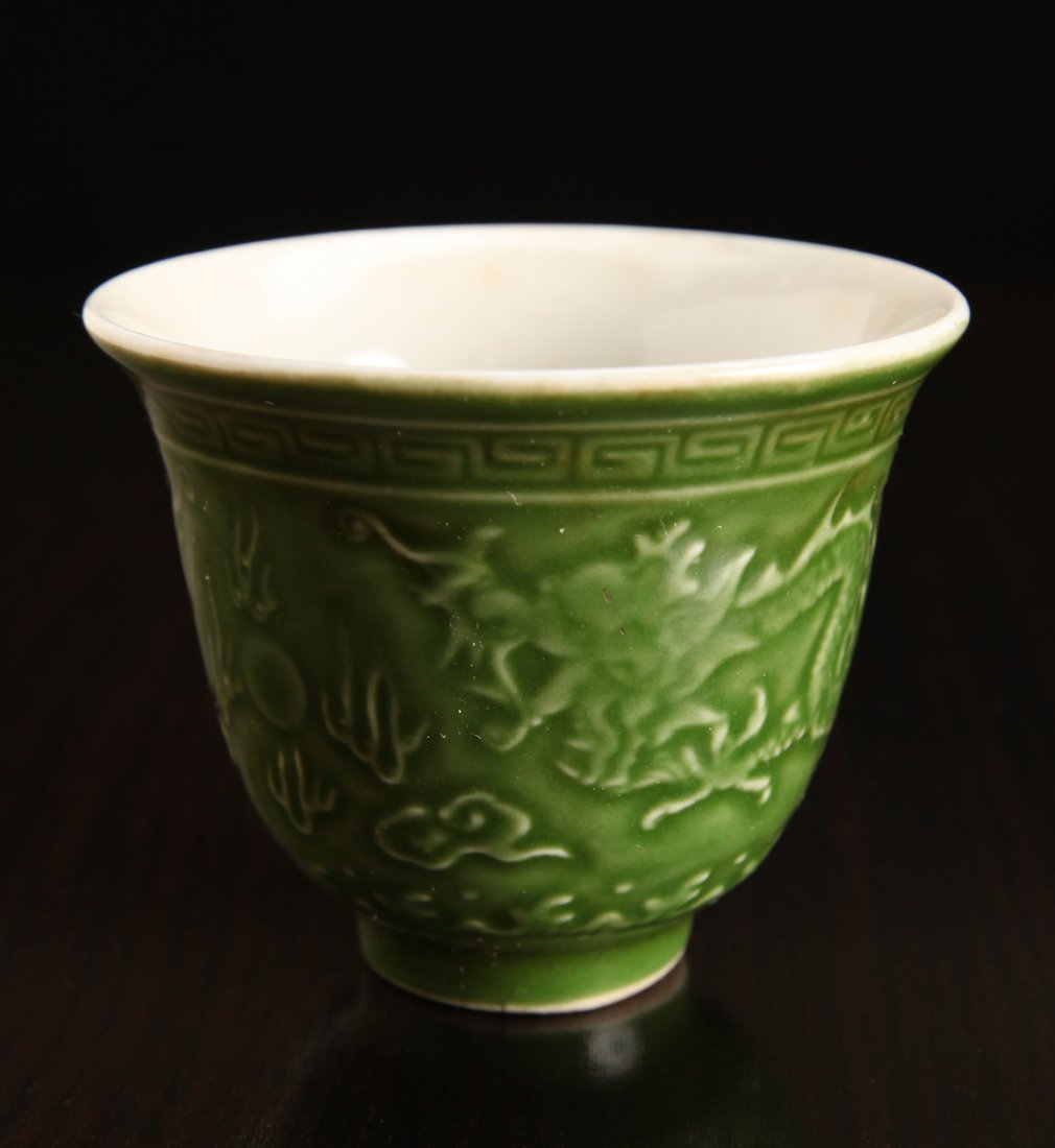 Chinese Incised Porcelain Wine Cup: In green with white interior, depicting dragons and ruyi. Six character mark in blue to underside. 2.25" H x 2.625" Dia. Two small firing cracks to foot.