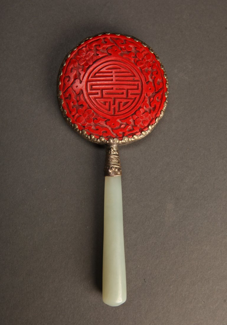 Chinese Cinnabar & Jade Hand Mirror: Back of mirror carved with Shou symbol in cinnabar or cinnabar style, with jade handle. 5.375" L x 2.25" W. Very good condition with slight wear.