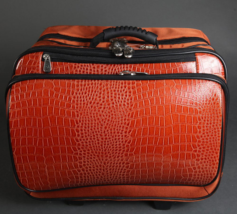 Joy Mangano Expandable Wheeled Briefcase: In burnt orange, with faux alligator. Appears unused. 15" H x 17" W. Odor present consistent with storage.