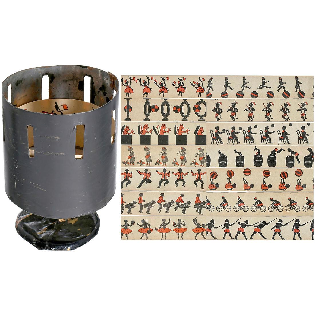 Miniature Zoetrope, c. 1890: Miniature Zoetrope, c. 1890 The tiniest tin toy "wheel-of-life" offered yet at auction! Tin drum and brass stand. With 7 twin-sided comic paper strips (approx. 1 1/5 x 7 in.), height 3 in. x 2 1/5 in.