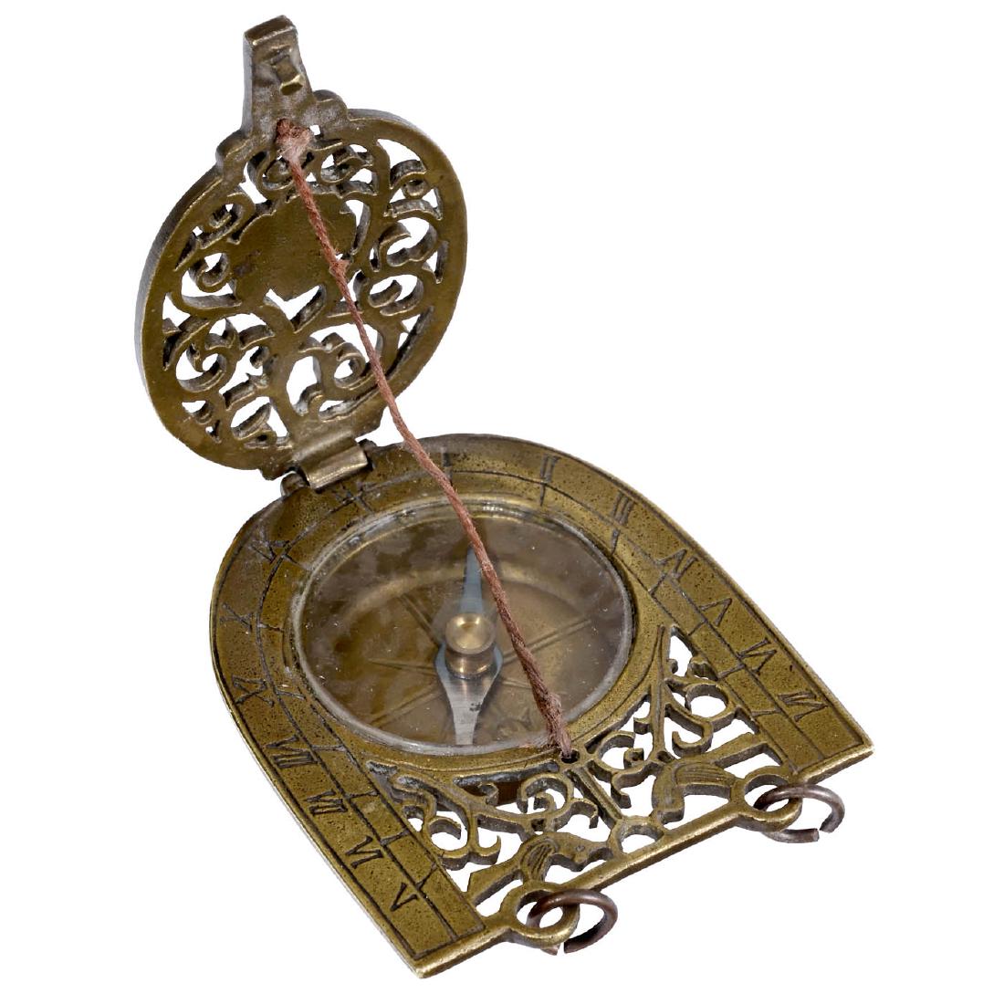 Miniature Folding Sundial, 18th Century: Miniature Folding Sundial, 18th Century Designed as a pendant, of horseshoe form, pierced brass, decorated with leaves, birds and blossom, engraved numerals, inset compass, hinged lid, string gnomon,