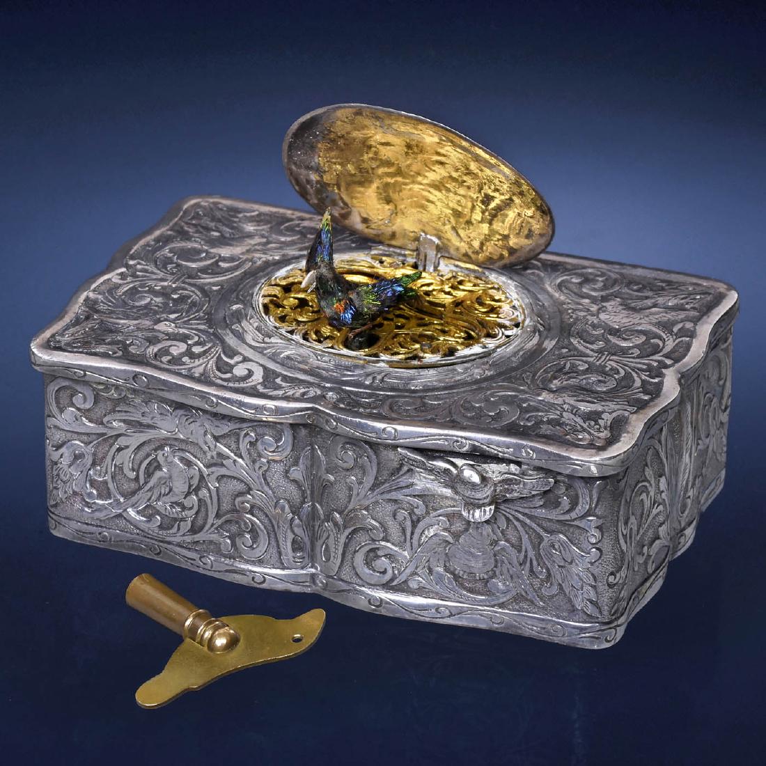 Singing Bird Box Automaton by Karl Griesbaum, c. 1930s: Singing Bird Box Automaton by Karl Griesbaum, c. 1930s Model 1, with going-barrel movement, bellows and whistle, bird with iridescent plumage, moving beak, wings and perch, in pressed white metal serp