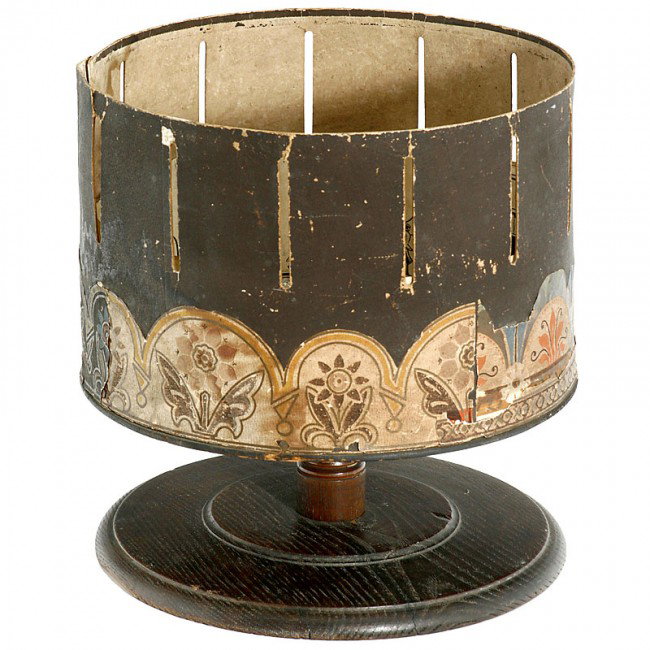 Zoetrope, c. 1870: Zoetrope, c. 1870 Milton Bradley & Co., USA. Very early "Wheel-of-Life" from USA, on wooden socket, tin drum Ø 11 3/4 in., height: 11 in., with approx. 28 original paper strips and 7 paper discs. - S