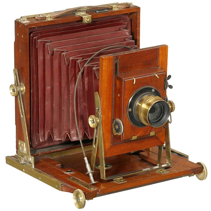 Shew's Universal Hand Camera, c. 1894: Shew's Universal Hand Camera, c. 1894 J. F. Shew, London. Field camera, size 5 x 7 in., polished wood with brass trim, dark-red bellows, lens: Carl Zeiss Anastigmat 1:7,2 F=195 mm, no. 9646, iris stop