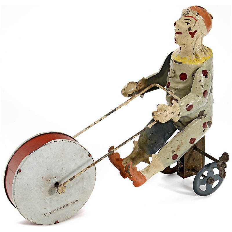 Günthermann Tin Toy Figure "Clown on Tricycle", c. 1910: Günthermann Tin Toy Figure "Clown on Tricycle", c. 1910 Clockwork-driven circus clown, hand-painted tin, large front wheel with simple musical movement, length 6 ½ in., working. Günthermann-Figur