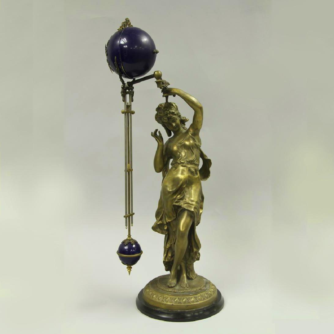 FRENCH MYSTERY CLOCK: FRANCE, A MYSTERY CLOCK, THE CLOCK FACE A BRIGHT BLUE COLORS WITH ARABIC NUMERALS AND MINUTE AND HOUR HANDS, LEADING DOWN AND TERMINATING IN A SMALLER BLUE PENDULUM, ALL HELD BY THE BRONZE SCULPTURE O