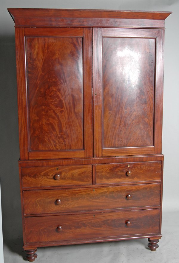 ENGLISH REGENCY MAHOGANY LINEN PRESS: in 3 parts. The removable projecting cornice above crotch paneled doors opening to four linen drawers. The lower case with 2 short drawers over 2 long drawers. Note lower drawers are fitted with aroma