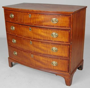 SMALL FEDERAL HEPPLEWHITE CHEST: having a hardwood case with bowfront and overhanging top, four graduated drawers with bold curly maple figured panels, surrounded by sap grain mahogany banding and retaining appropriate oval brass pul