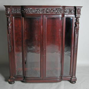 IMPORTANT VICTORIAN MAHOGANY CHINA CABINET: exquisitely carved frieze and sides having two paneled bowed and straight glass doors. Attributed to Horner of New York. Complete with 4 original shelves. Ht. 63 1/2", W. 57", D. 17 1/2". Provenance: