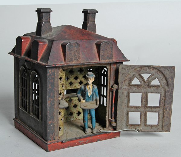 NOVELTY BANK, OPENING DOOR & TELLER, MECHANICAL: BANK, circa 1870-1880, made by J. E. Stevens, in building form with door opening to reveal tellers, works by placing coin in tray that teller holds ad when door is closed he deposits it throu slot in 