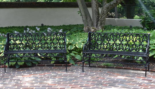 CHOICE PR OF CAST IRON GOTHIC DESIGN GARDEN BENCHES: The design attributed to the Coalbrookdale foundry. The benches in the Gothic Revival English taste featuring Gothic tracery backrest centered by quatrefoil designs. The gracefully curved arms with Go