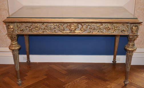 18TH CENTURY ITALIAN GILTWOOD CONSOLE TABLE: The Italian Louis XVI console table is raised by fine gilt fluted tapered legs topped with acanthus carved capitols, the frieze with central grotesque mask with scroll work acanthus and floral decorat