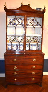 FINE ENGLISH REGENCY MAHOGANY SECRETARY BOOKCASE: The upper case with pediment top with central rectangular panel with oval inlay topped with four brass urn finials above two hinged glazed doors with Gothic arched muntins and brass t astragal above a