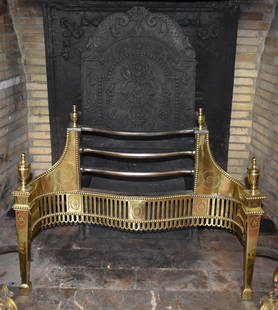 ENGLISH ADAMS PERIOD BRASS RETICULATED COAL GRATE: The grate with cast iron arched back with paired dolphin form crest above a central panel featuring an English rose, the front with three bowed steel rails flanked by a bead decorated engraved brass f