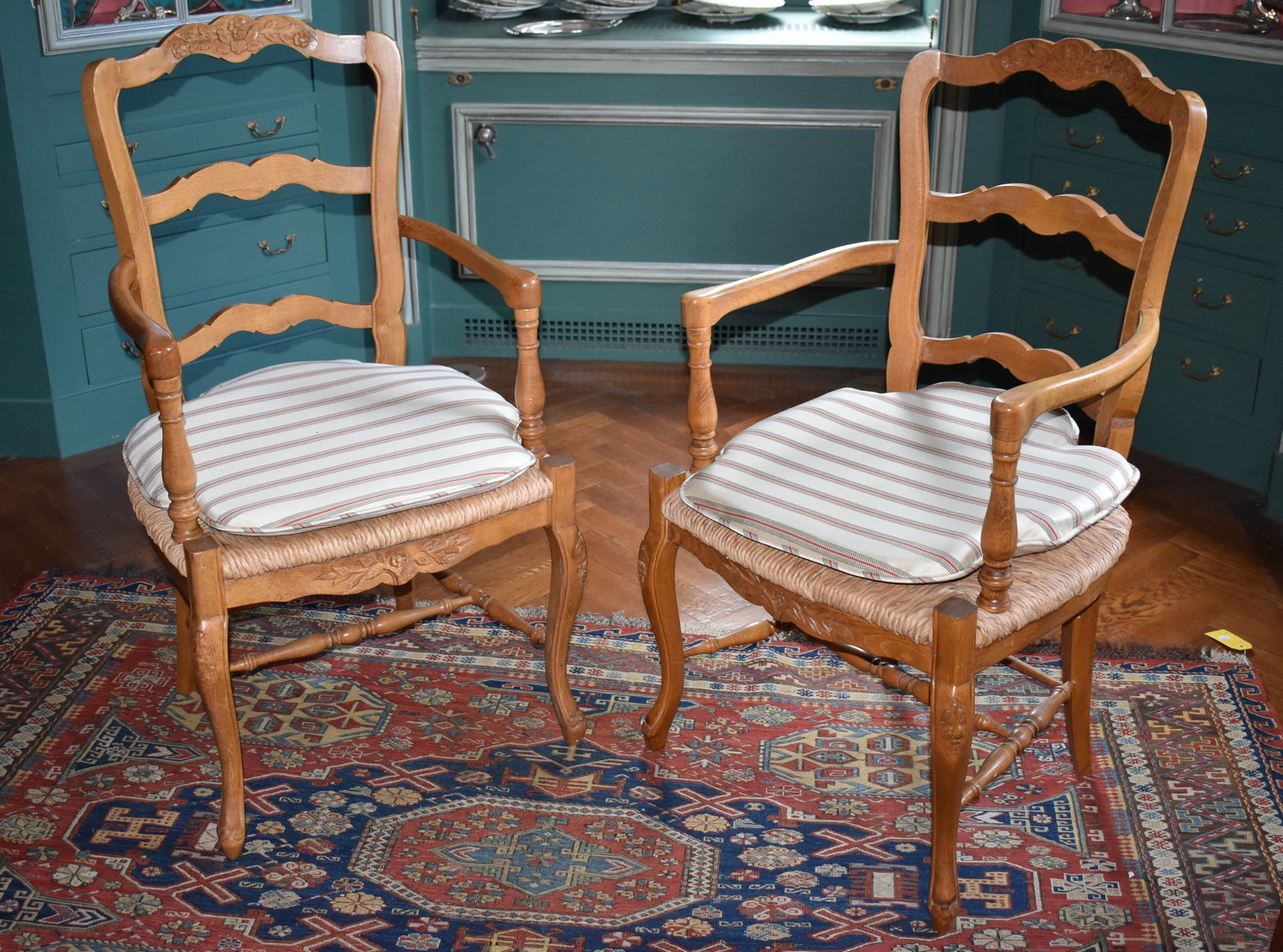 PAIR OF LOUIS XV COUNTRY FRENCH ARMCHAIRS: The Louis XV style country French fruitwood armchairs with floral carved serpentine crest rail above two shaped splats and turned arm supports, the rush seats fitted with striped pillow on cabriole le