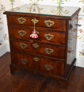 GEORGE II ENGLISH WALNUT BACHELOR'S CHEST: The chest with bookmatched quarter panel banded veneered molded rectangular top above four graduated banded veneered drawers with original openwork brasses. The case resting on straight bracket feet.