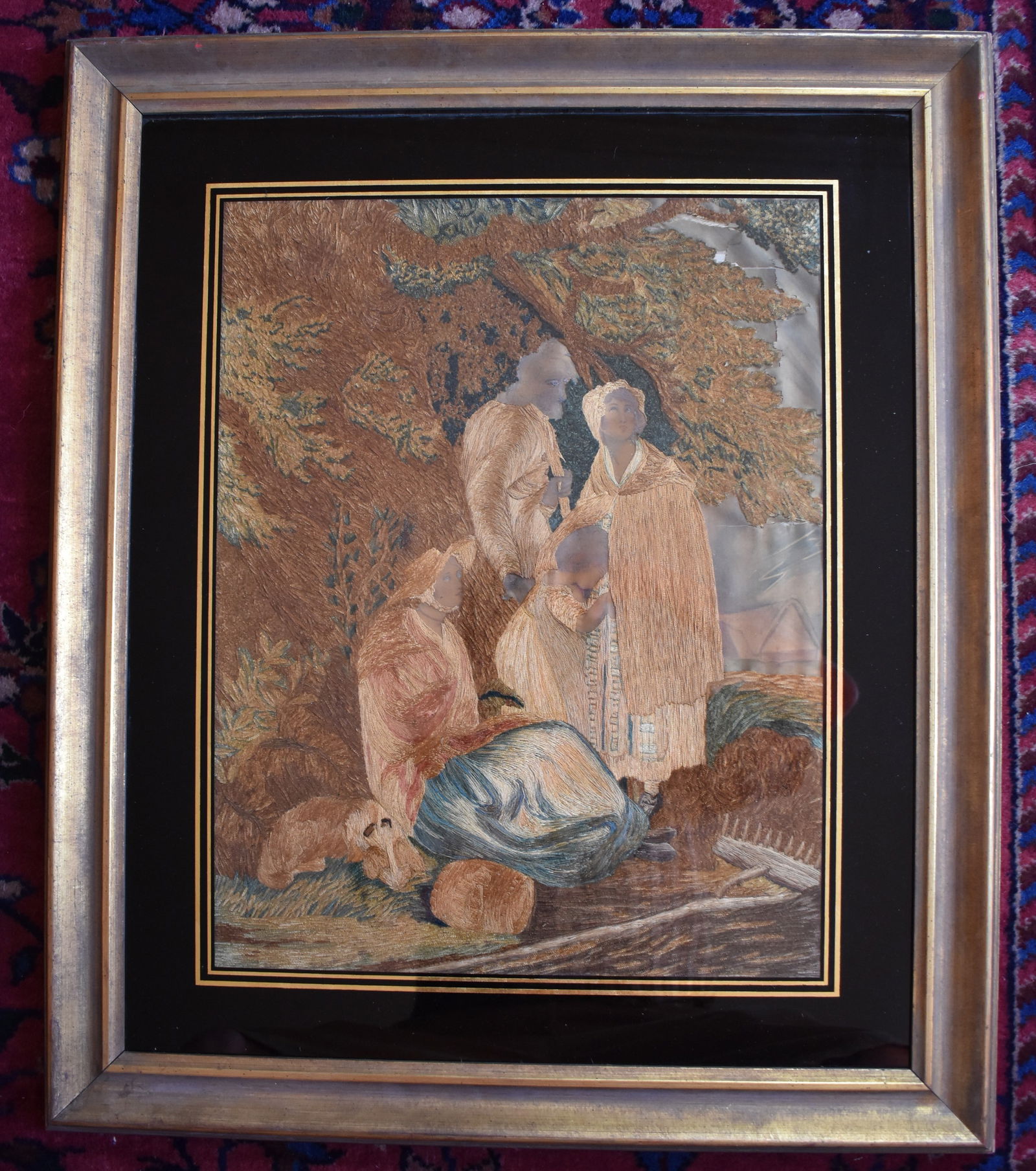 EARLY 19TH CENTURY ENGLISH SILK NEEDLEWORK: Depicting a farmer's family in bucolic English landscape under eglomise glass in molded gilt frame. 25 1/2" x 22"