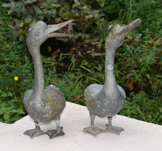 PAIR OF CAST BRONZE ORNAMENTAL GARDEN DUCKS: One duck with detached leg. Height 17"