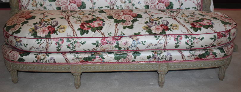 FINE LOUIS XVI FRENCH CRÈME PAINTED BED STOOL: The Louis XVI upholstered bed stool in crème paint with floral upholstered down cushion and frame with guilloche and rosette carved skirt on tapering fluted carved legs. Length 62" Height 13 1/2" D