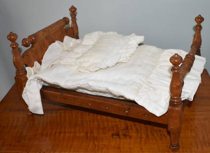 19TH CENTURY AMERICAN TIGER MAPLE DOLL'S BED: The tiger maple doll's bed with rolling pin headboard, ball and baluster turned tapering posts. The footboard with medial turned stretcher connecting posts. Rails with holes for rope. 9 1/2" x 16" x 1