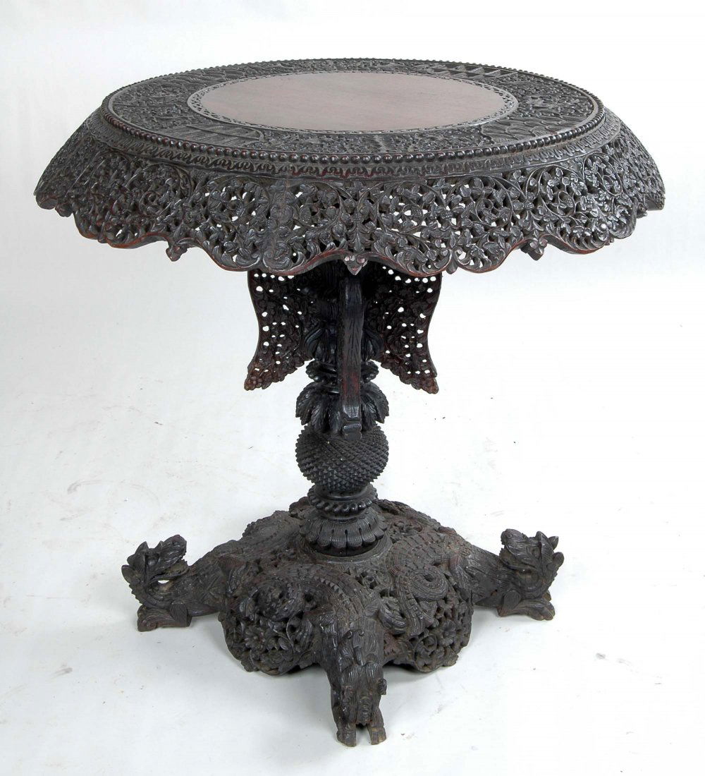 ANGLO-INDIAN HARDWOOD CENTER TABLE: The circular top having an extraordinary deep three dimensional reticulated carved frieze, set on elaborate four winged and pineapple carved support, having four animal carved feet. 19th century. Ht.