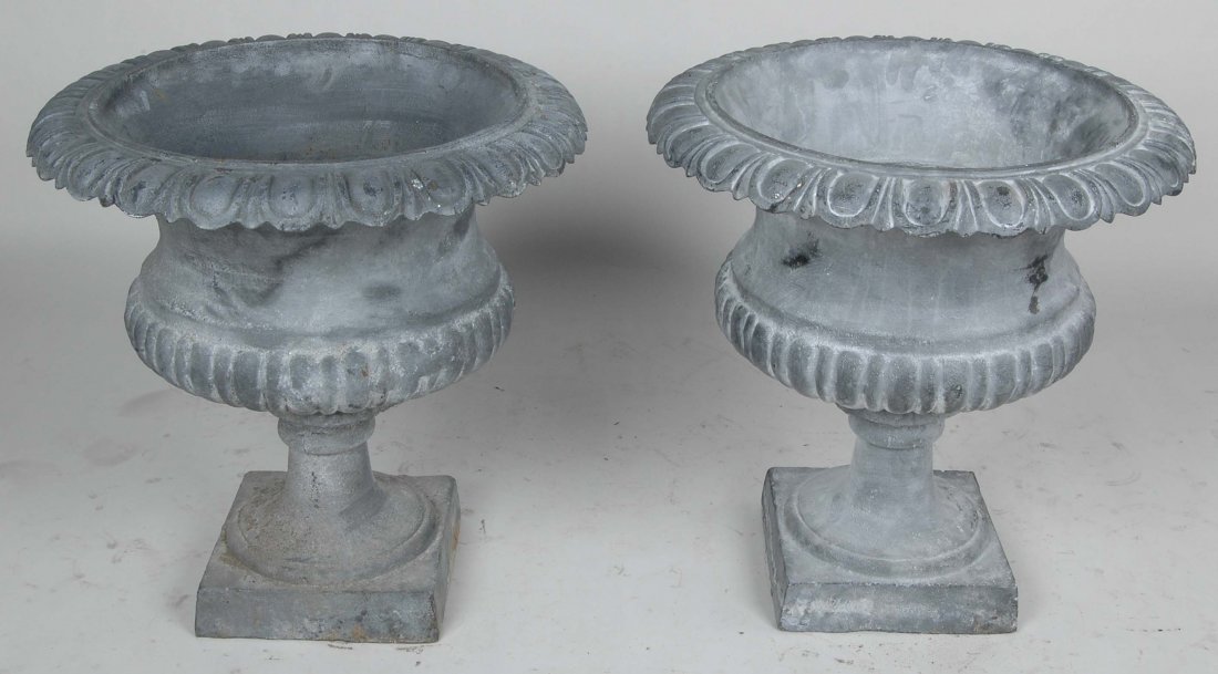 PAIR OF CLASSICAL CAMPAGNA FORM URNS: The lead patinated bodies having an egg and dart flared lip border with lobed bodies on rectangular plinths. H. 23 1/2" Dia. 23"