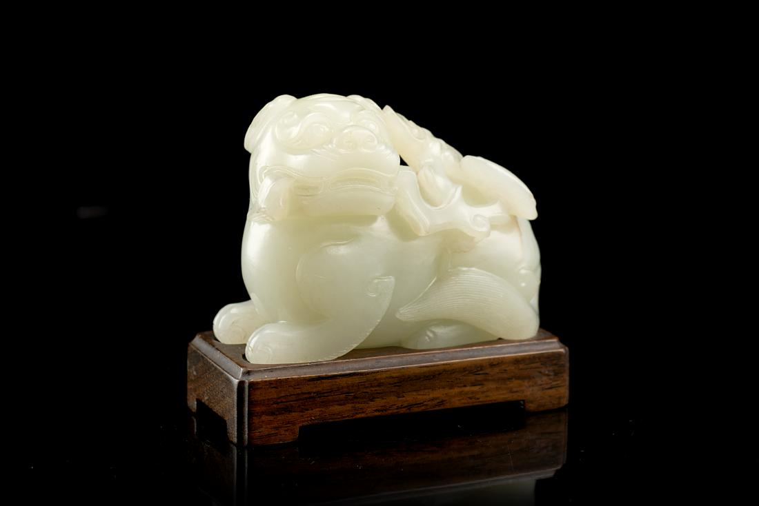 A pale celadon jade model of a Buddhist lion, wood base (1 of 1)