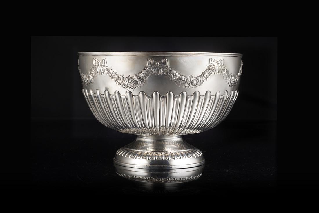 A silver bowl. London, 1898. Silversmith William Hutton: A silver bowl. London, 1898. Silversmith William Hutton & Son LTD (d. cm 31 ca.; h. cm 20 ca.) (g 1490 ca.) (minor defects) IT Bowl in argento decorata da fasce di baccellature radiali e festoni di fi