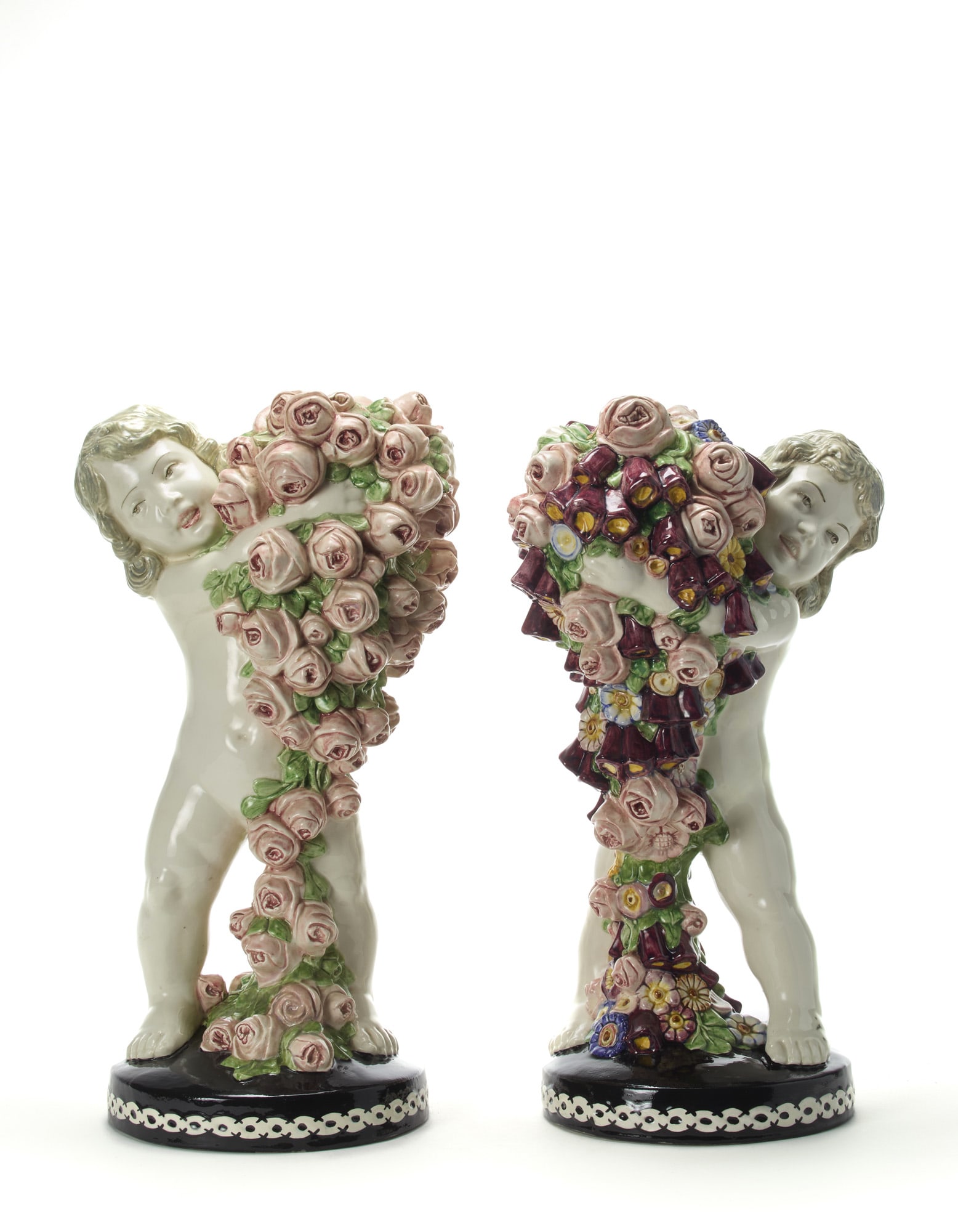 Carl Klimt (1876 - 1945) Two sculptures depicting a putto with roses and a putto with flowers and: Carl Klimt (1876 - 1945) Two sculptures depicting a putto with roses and a putto with flowers and roses. Execution by Bernhard Bloch, Austria, 1915ca. Cast ceramic enamelled in polychromy under glaze.