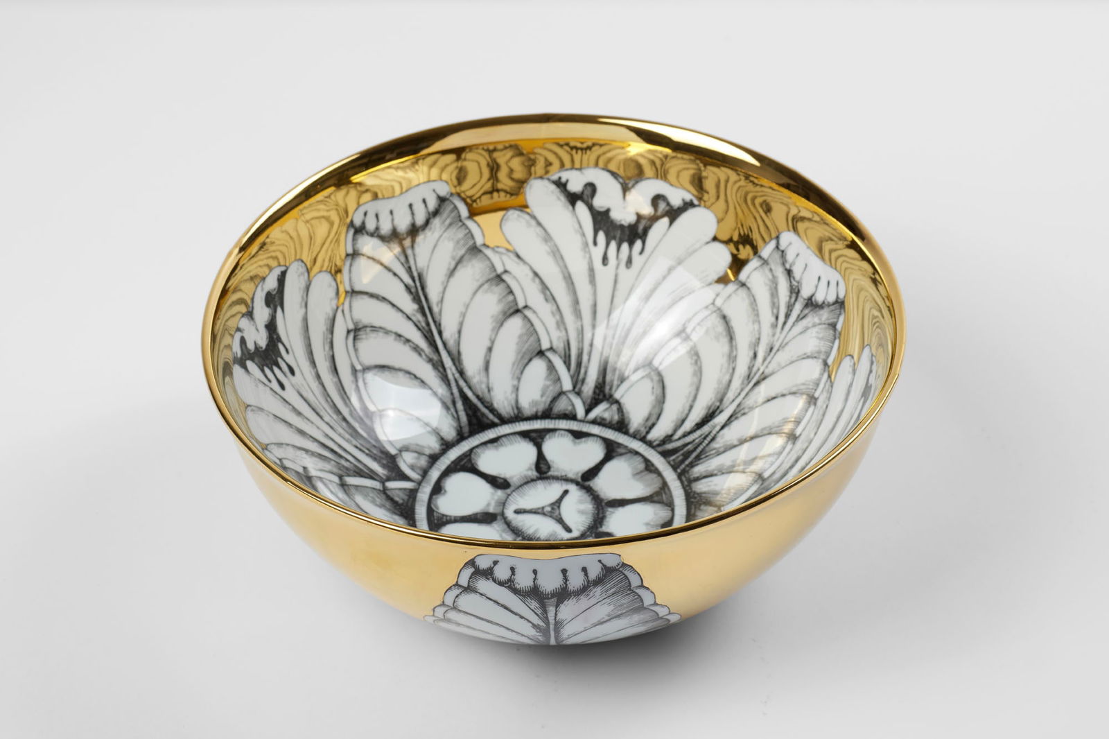 Fornasetti Ceramic bowl screen-printed in black and gold. Milan, recent production. In original: Fornasetti Ceramic bowl screen-printed in black and gold. Milan, recent production. In original box. (h 12 cm.; d 28.5 cm.) (slight defects) IT Ciotola in ceramica serigrafata in nero e oro. Milano, p