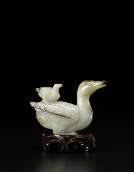 A celadon and russet jade duck group, the birds: A celadon and russet jade duck group, the birds depicted crouched one on top of the other, fine incised details of the beak and the feather, the stone with natural flaw lines and darker inclusions, wi