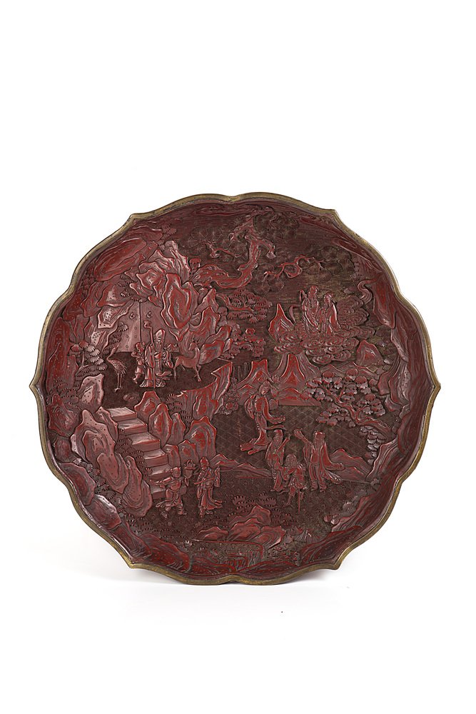 A resin lobed dish decorated with the Eight: A resin lobed dish decorated with the Eight Immortals in a mountainous landscaped, the back with Buddhist symbols, apocryphal Qianlong mark China, 19th century (diam. 31 cm.)