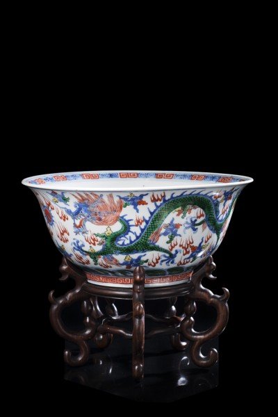 A large wucai porcelain bowl decorated with two: A large wucai porcelain bowl decorated with two five-clawed dragons chasing the flaming pearl, with an apocryphal Wanli mark to the base, with wood base China, sec. XIX (diam. 28,5 cm.)