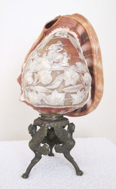 EARLY 20TH CENTURY CARVED CAMEO CONCH SHELL: EARLY 20TH CENTURY CARVED CAMEO CONCH SHELL AND STAND Ornately carved cameo with a lady playing the violin, and child surrounded by flowers. On a brass stand.
