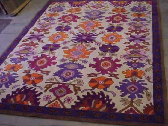 EDWARD FIELDS FLORAL RUG: EDWARD FIELDS FLORAL RUG. COLORS ARE PURPLE,BURGUNDY,ORANGE, IN A CREAM FIELD WITH BROWN BORDER.DATED 1981. SIZE, 6' X 8'
