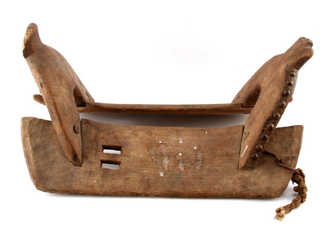 ANTIQUE EARLY NATIVE AMERICAN WOODEN SADDLE: Early wooden saddle with copper rivets along the sides. Two rectangular perforations to each side of seat. Measures 20 by 11.5 by 9.5 inches. Wear commensurate with age.