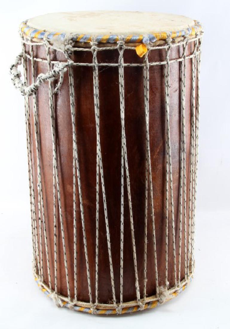 NATIVE AMERICAN LEATHER RAWHIDE AND WOODEN DRUM: Vintage Pow Wow Drum. Made of a hollow log with double ended rawhide skin it measures 23" tall and 16" across. With decorative yellow and blue ribbon on both ends, moderate wear from usage.