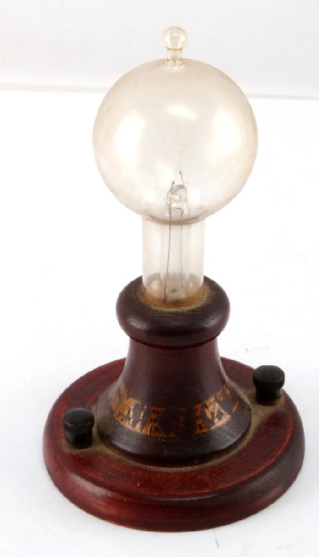 VINTAGE ANTIQUE GLASS LIGHT BULB: One vintage antique light bulb. Item is on a wooden stand, and has not been tested for function.