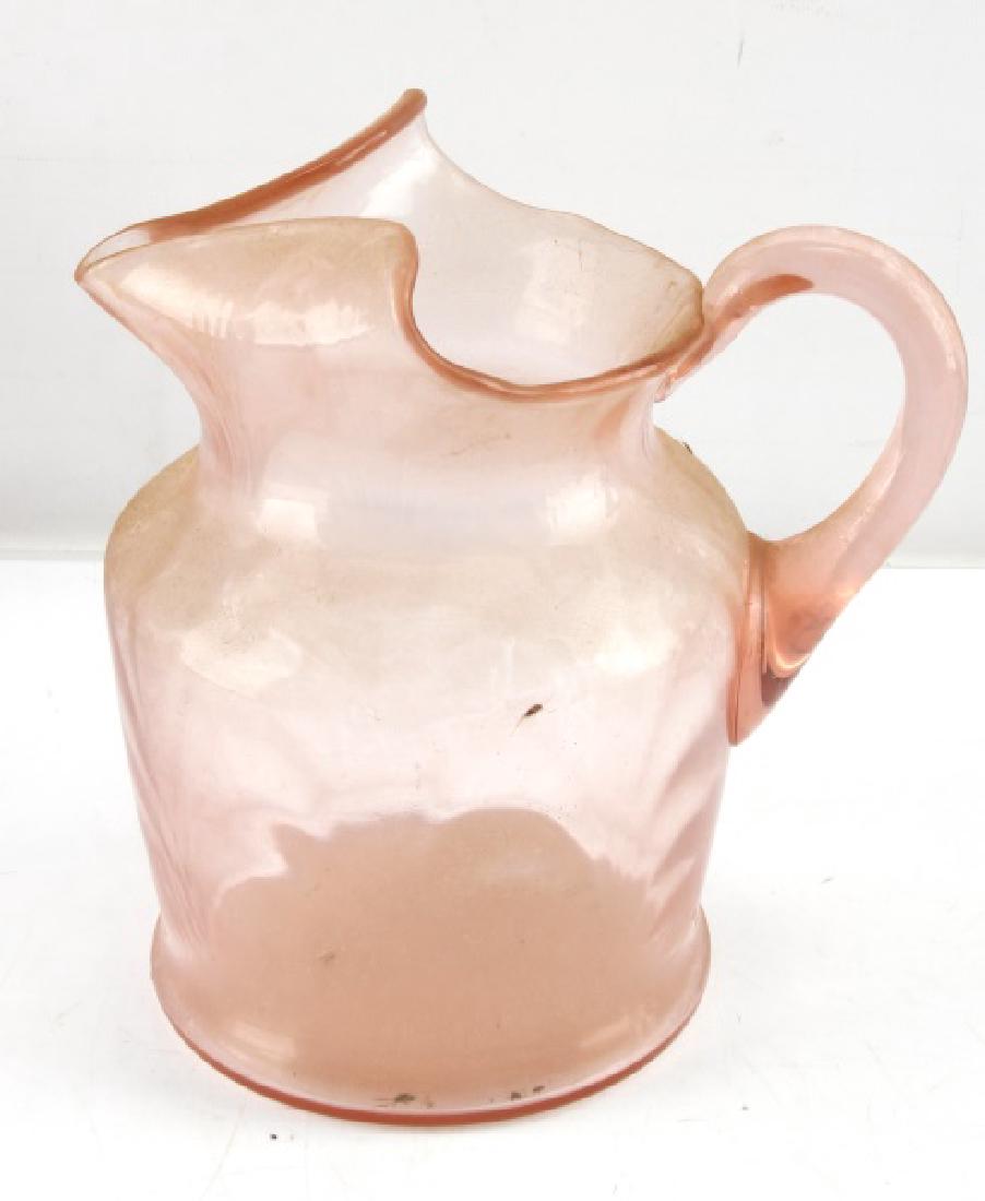 ANTIQUE ROSE COLORED DEPRESSION ERA GLASS PITCHER: Antique rose-colored Depression era Glass pitcher with hand-blown handle & curved lip. Measuring 8'' tall and 4'' in diameter at widest point this rare and intricate depression era pitcher is in very